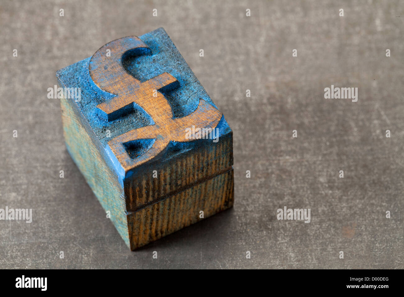 Währungssymbol Pfund - Vintage Buchdruck Holzart Block befleckt durch blaue Tinte auf Metall Grunge Hintergrund Stockfoto