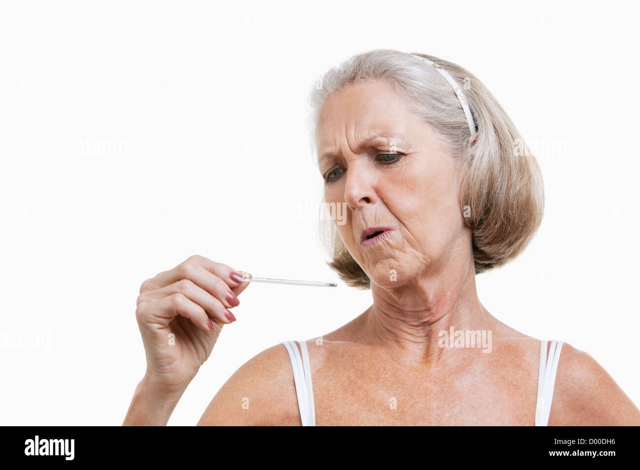 Besorgt senior Frau prüfen Thermometer vor weißem Hintergrund Stockfoto