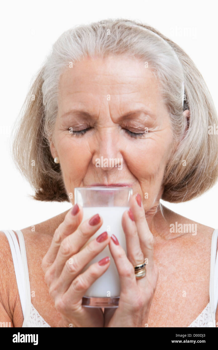 Ältere Frau trinkt Milch vor weißem Hintergrund Stockfoto