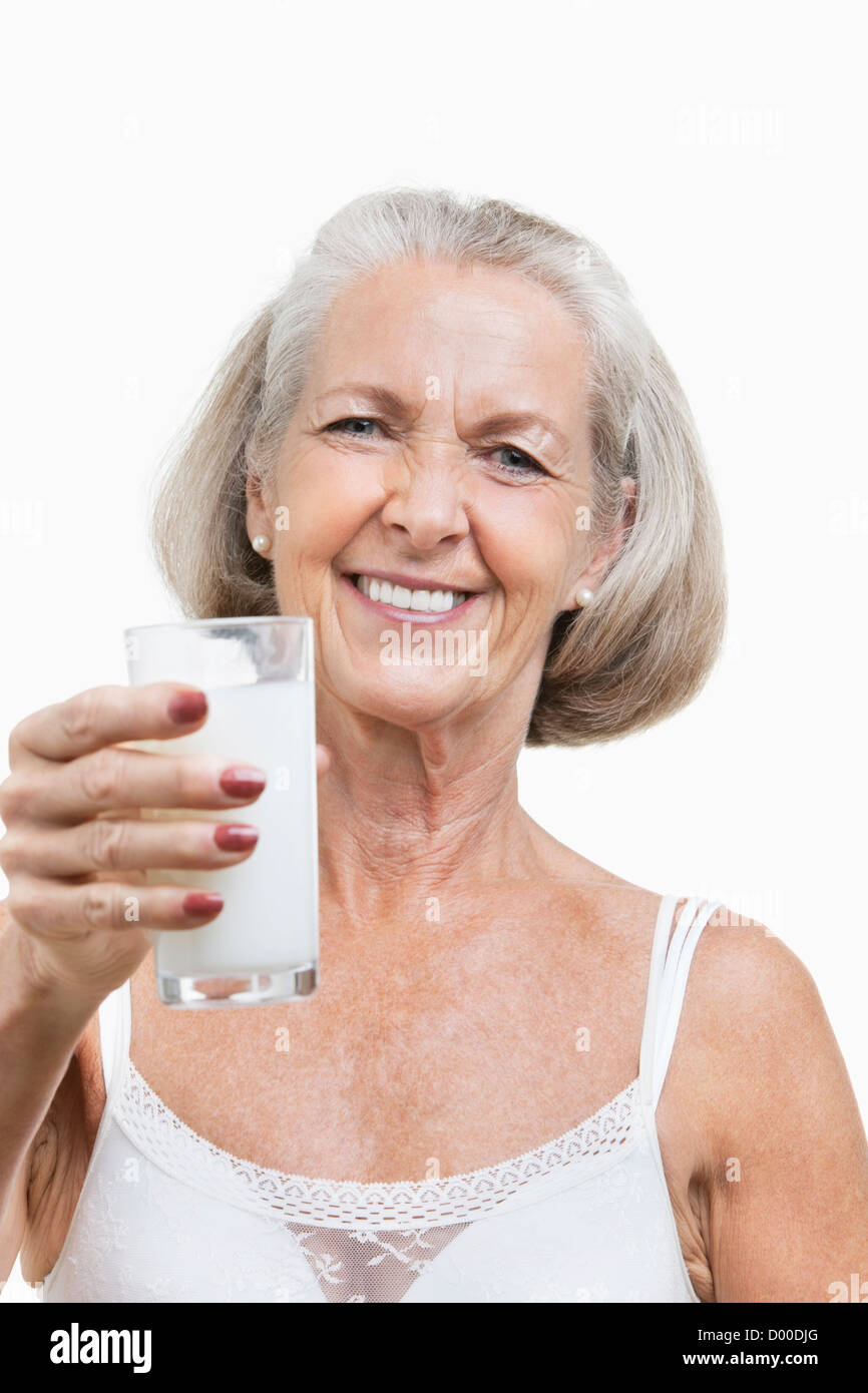 Porträt der lächelnde ältere Frau mit einem Glas Milch auf weißen Hintergrund Stockfoto