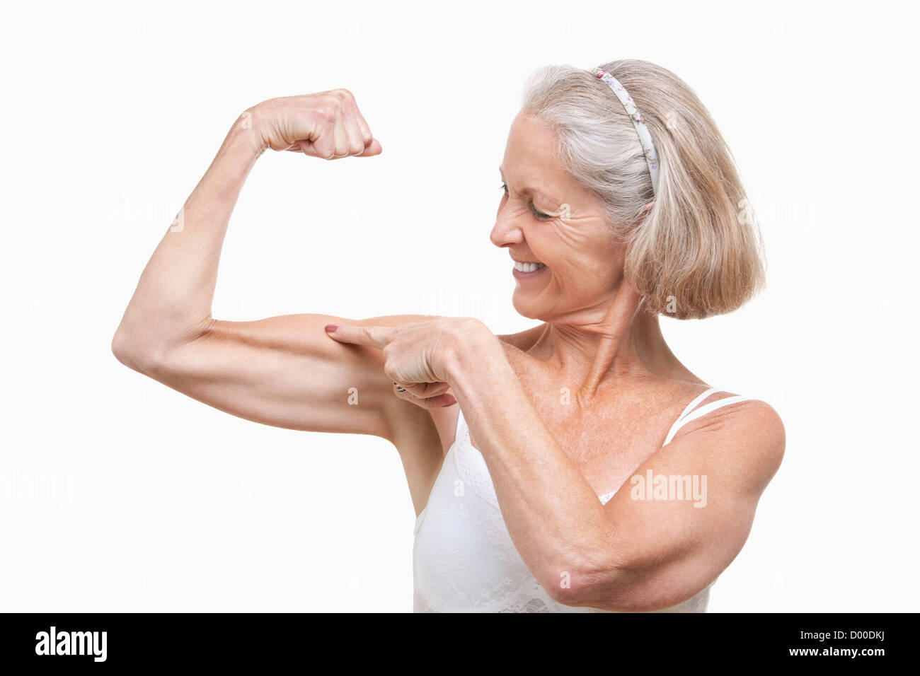 Ältere Frau, die Muskeln vor weißem Hintergrund Stockfoto