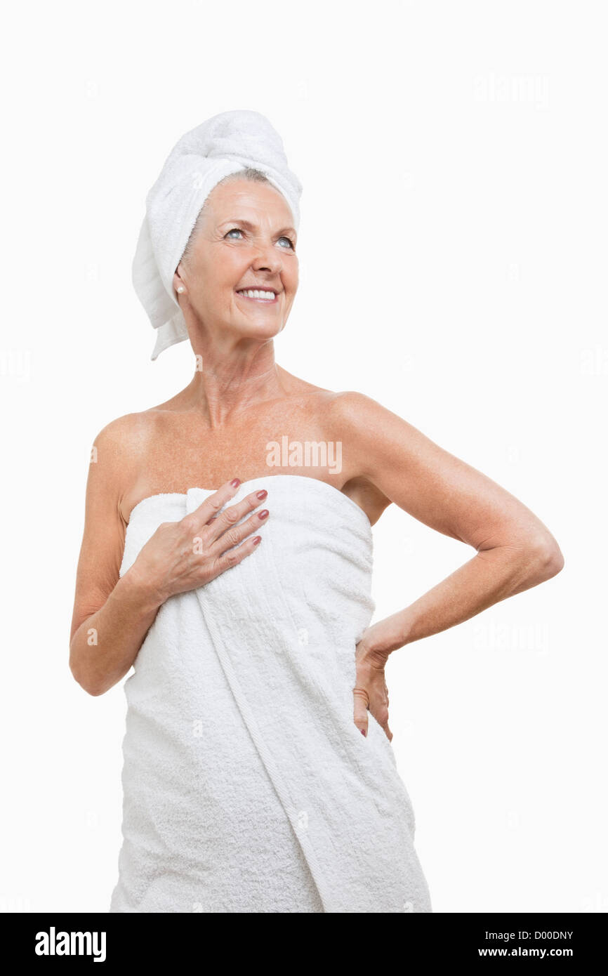 Lächelnde senior Frau eingewickelt in Tücher vor weißem Hintergrund Stockfoto