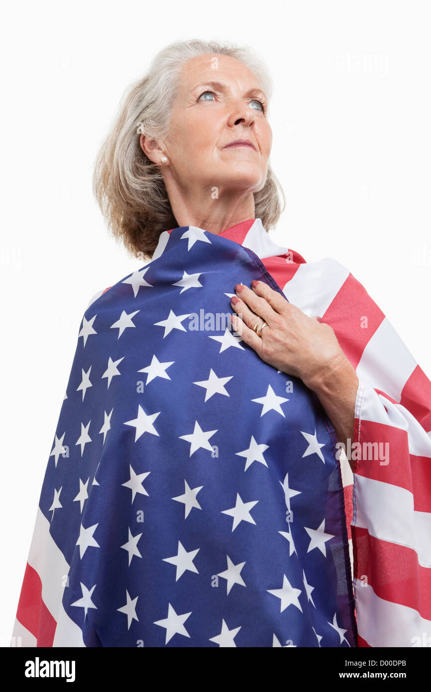 Ältere Frau eingewickelt in amerikanische Flagge vor weißem Hintergrund Stockfoto