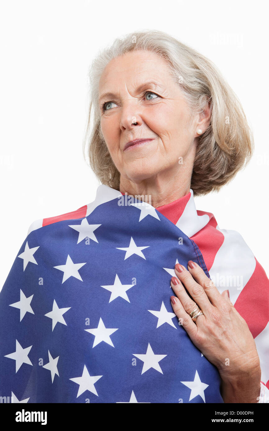 Ältere Frau eingewickelt in amerikanische Flagge vor weißem Hintergrund Stockfoto