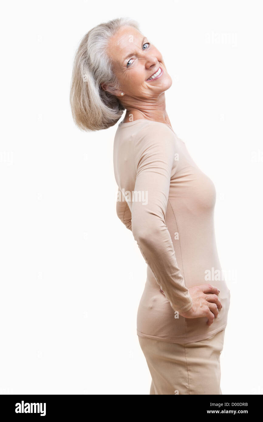 Seitenansicht der älteren Frau in Casuals mit Hände auf den Hüften vor weißem Hintergrund Stockfoto