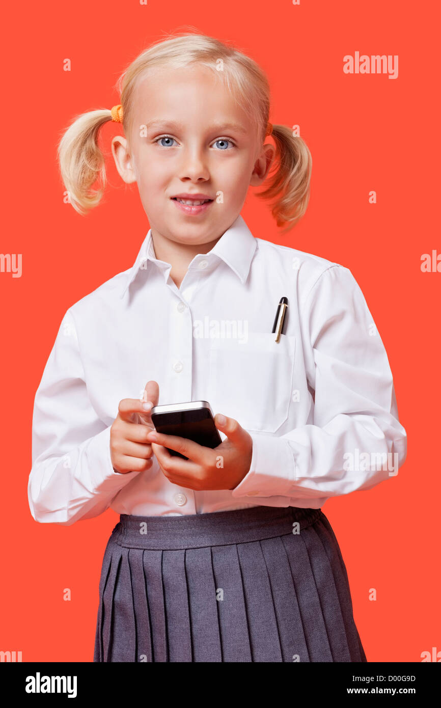 Porträt einer jungen Schülerin mit Handy über blauem Hintergrund Stockfoto