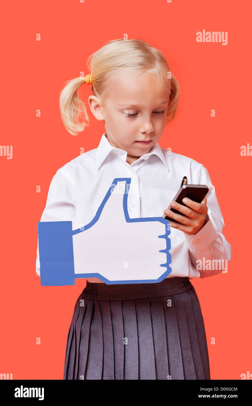 Junge Schülerin mit Handy halten gefälschte like-Button orange Hintergrund Stockfoto