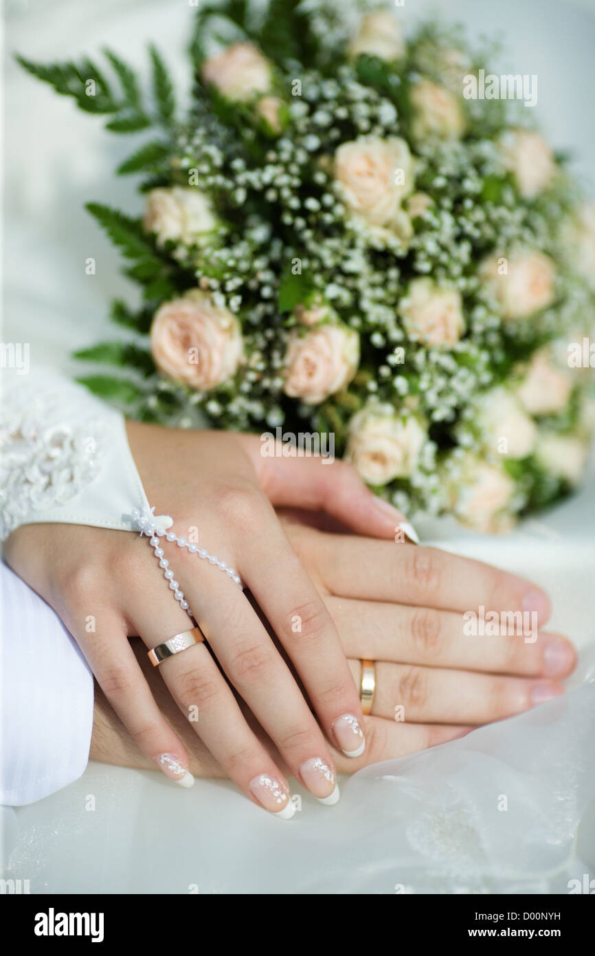 Händen der neuen verheiratet mit goldenen Ringen und Blumenstrauß Stockfoto