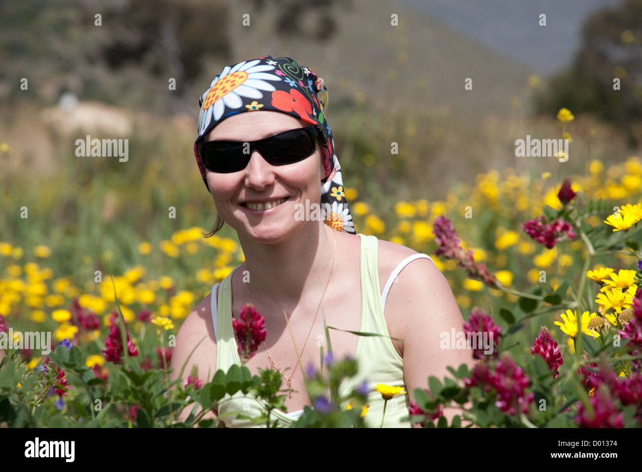 Porträt der lächelnde Frau in sonnigen Sonnenbrille unter Wild Sommerblumen Stockfoto