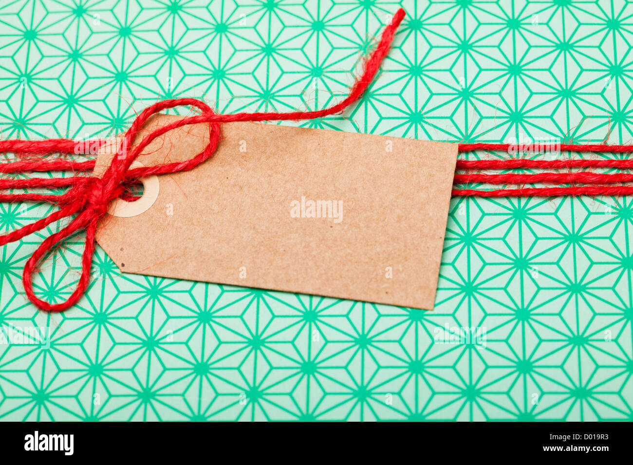 Nahaufnahme eines einfachen Geschenk in grünen Verpackung mit roter String und braunen Karton tag Stockfoto