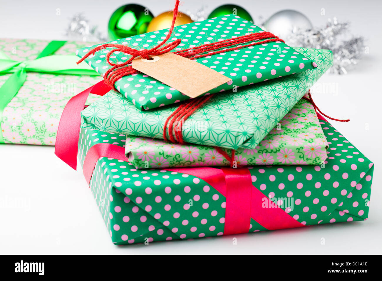 Verpackte Weihnachtsgeschenke mit leeren Tag und Christbaumkugel Dekorationen Stockfoto