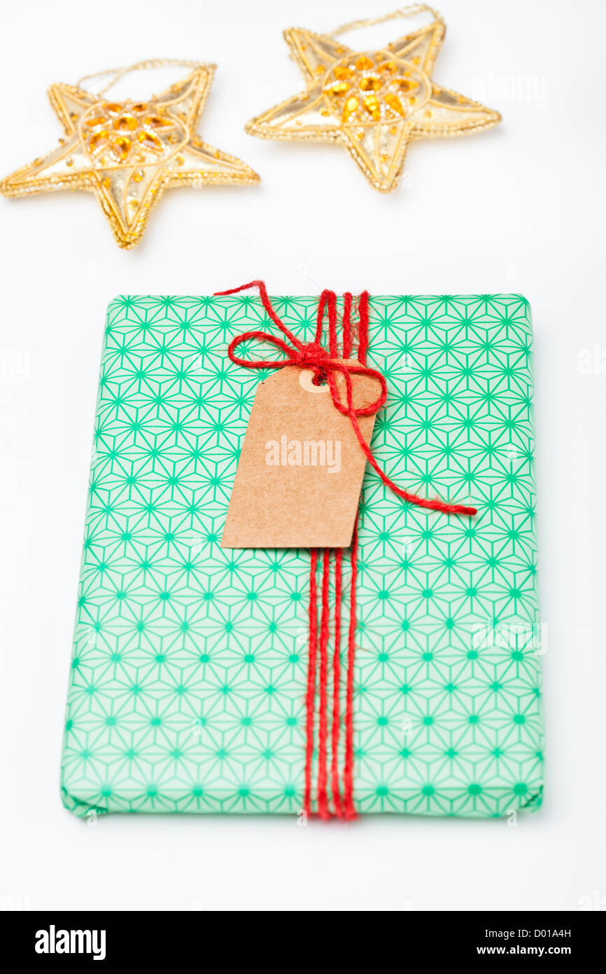 Einfach verpacktes Geschenk mit einfachen Umbau und Sterne Dekorationen auf weißem Hintergrund Stockfoto