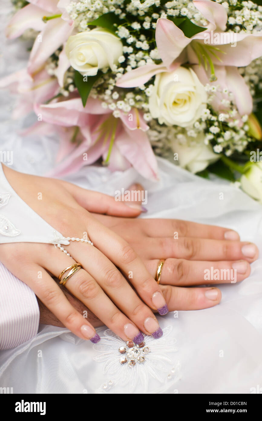 Händen der neuen verheiratet mit goldenen Ringen und Blumenstrauß Stockfoto