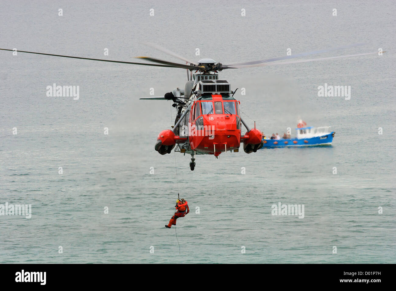 Ein Winchman, der während einer Seerettungsübung von einem Such- und Rettungshubschrauber in Newquay, Cornwall, S W England, abgesenkt wird. Stockfoto