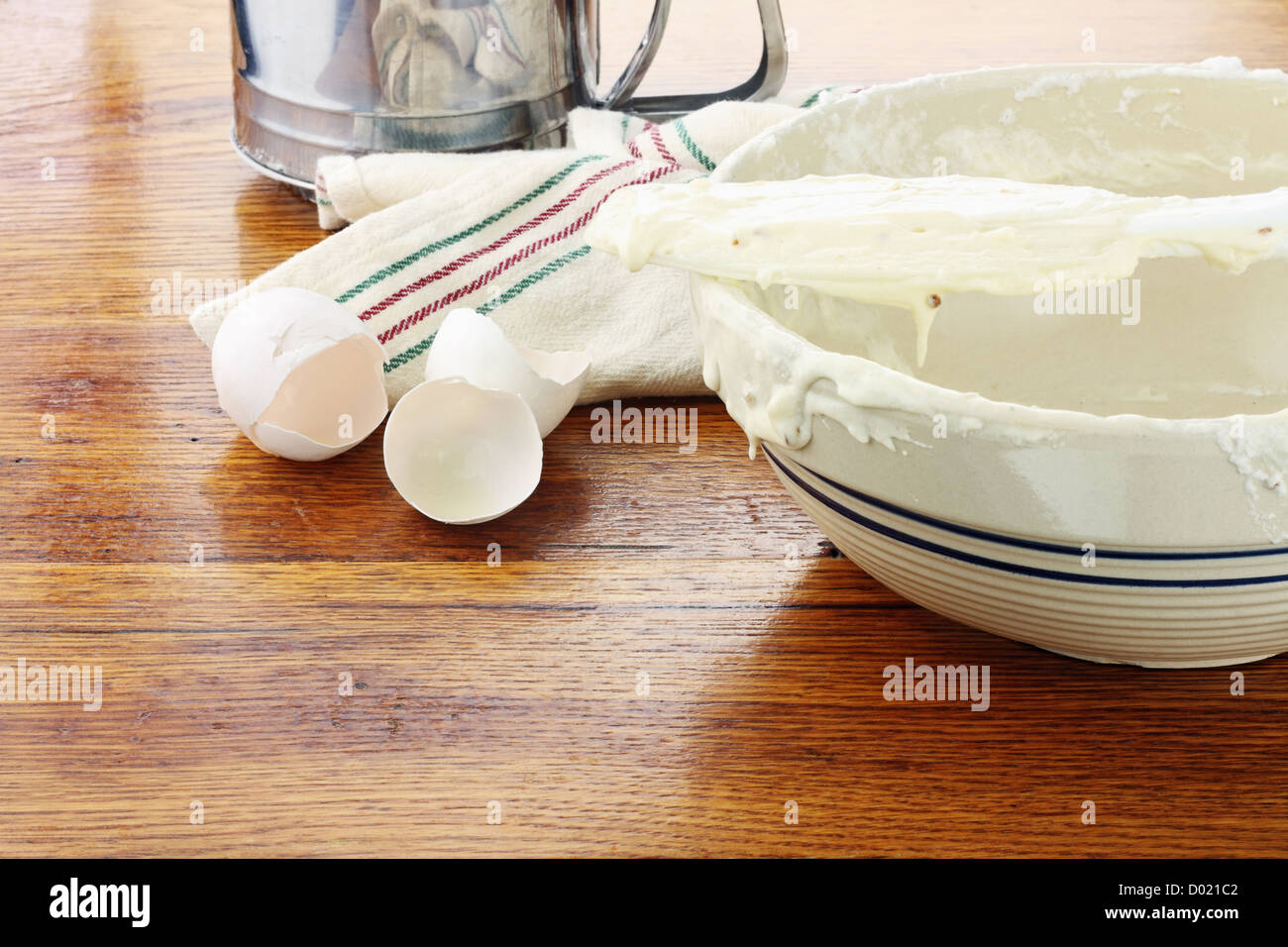 Alte Mode Rührschüssel mit Kuchenteig oder Pfannkuchenteig sitzt auf einem rustikalen Holztisch. Stockfoto