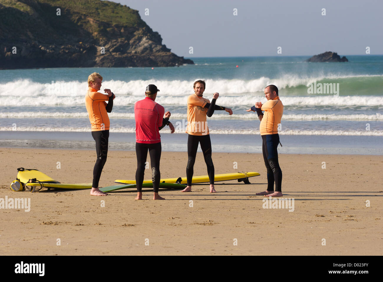 Surfer machen ihre Pre-Surf-Übungen mit ihrem Instruktor in Newquay, Cornwall, Südwestengland Stockfoto