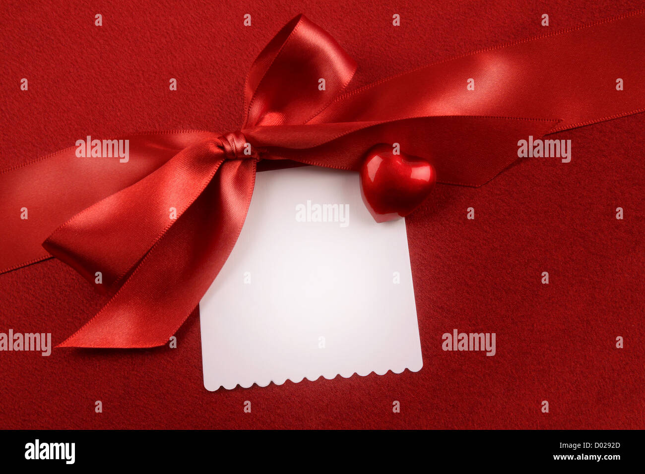 Satin-Schleife und weiße Karte für Geschenk auf rotem Grund Stockfoto