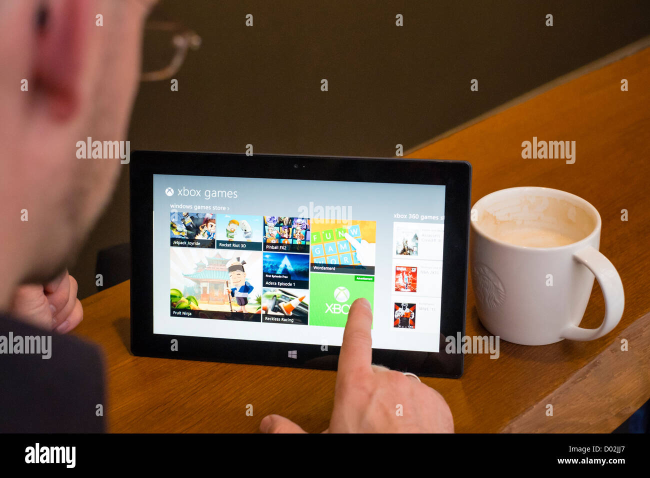 Mann mit Microsoft Surface rt Tablettcomputer Spiele im AppStore durchsuchen Stockfoto