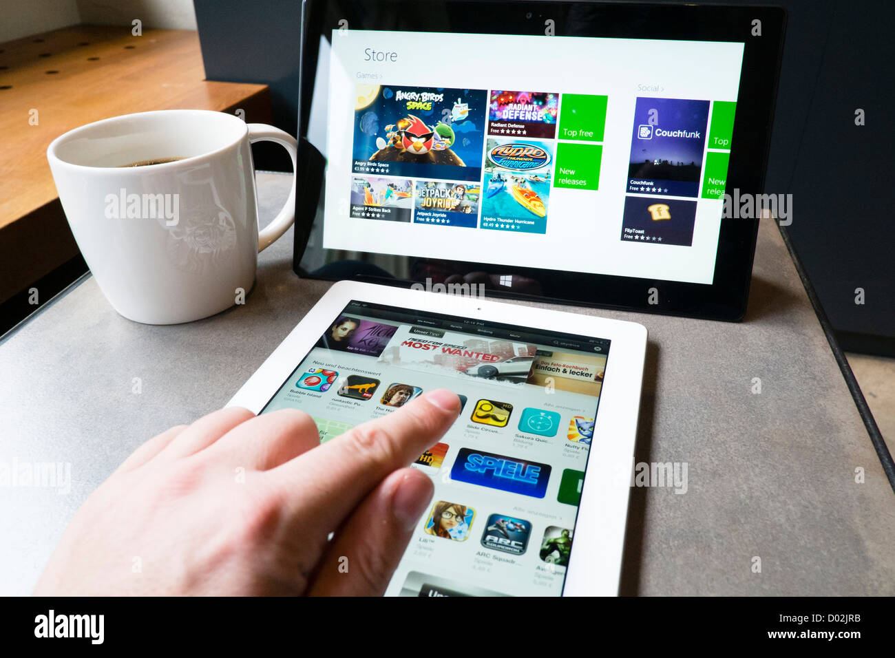 Mann mit iPad 3 und Microsoft Surface rt Tablet PC app-Stores im Café Surfen Stockfoto