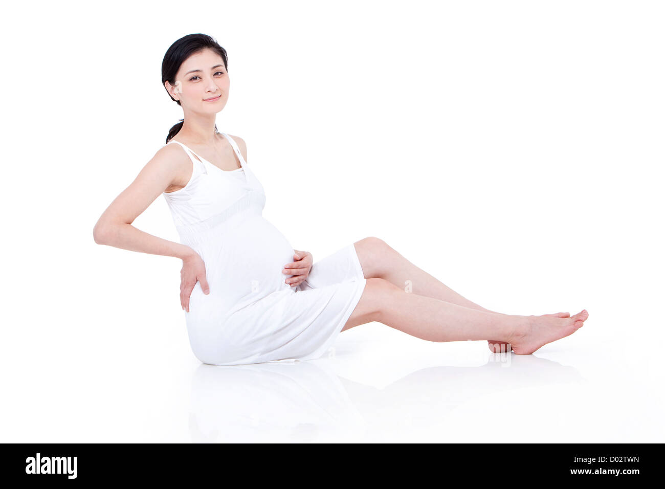 Fröhliche schwangere Frau am Boden Stockfoto