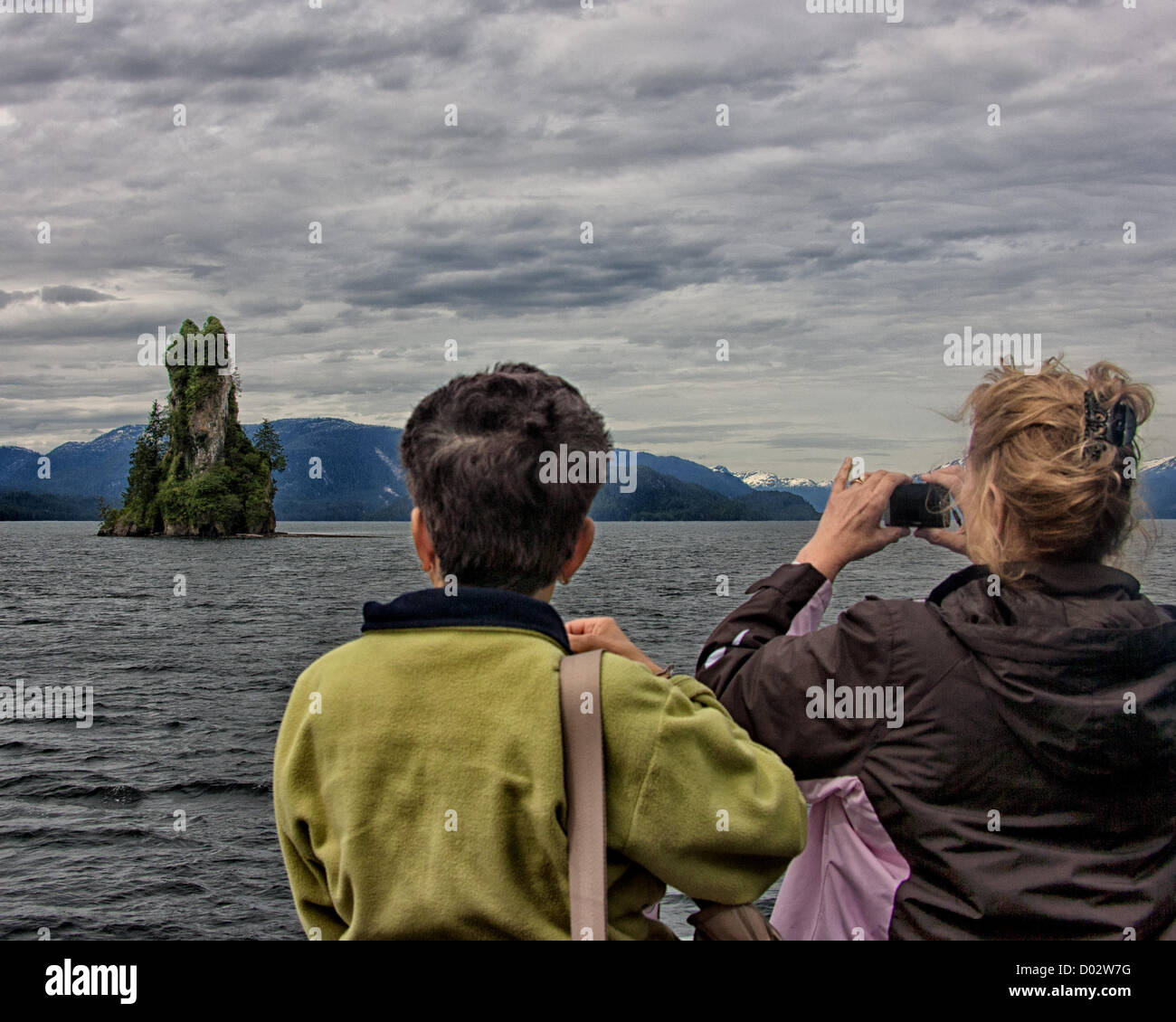 6. Juli 2012 - Ketchikan Gateway Borough, Alaska, USA - Urlauber auf einem Ausflugsboot sehen und fotografieren die neue Eddystone Rock in Misty Fjords Behm Canal. 237-Fuß hohen Basalt Säule, der Überrest eines vulkanischen Steckers erstellt von Lava vor 5 Millionen Jahren seine gebrochene, planlose Textur gibt an, dass es gehörte einem Vulkanschlot wo stieg Magma immer wieder an die Oberfläche der Erde. Immergrüne Wachstum hat sich heute auf dem Felsen etabliert. Misty Fjords National Monument und Wildnis-Gebiet, entlang der Inside Passage Küste der südöstlichen Alaska wird verwaltet von der US Forest Service und co Stockfoto