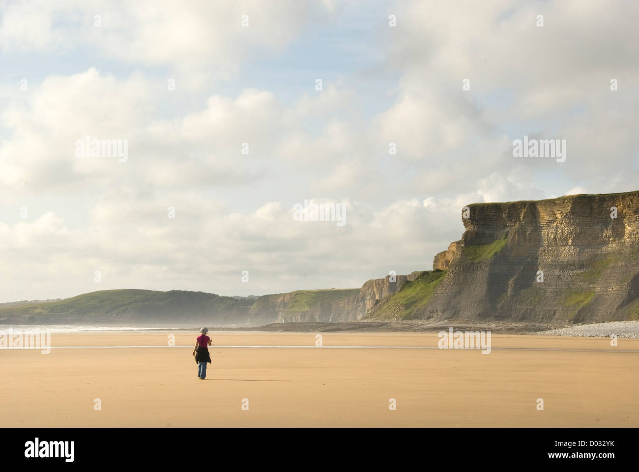 Frau zu Fuß entlang riesigen Sandstrand, Southerndown, in der Nähe von Nash Point, Glamorgan Heritage Coast, Wales, UK Stockfoto