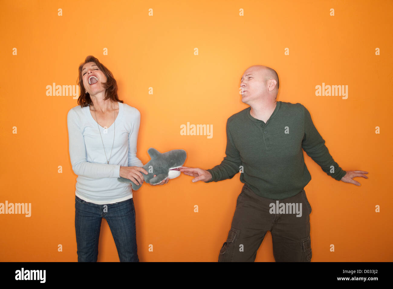 Frau beißt glatzköpfiger Mann Finger mit Hai Spielzeug Stockfoto