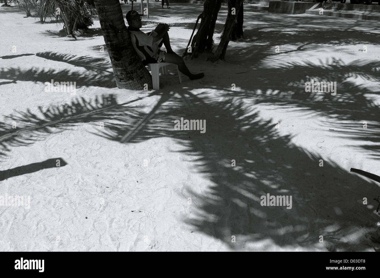 Strand-Verkäufer sitzt unter Schatten der Palme, Thailand Stockfoto