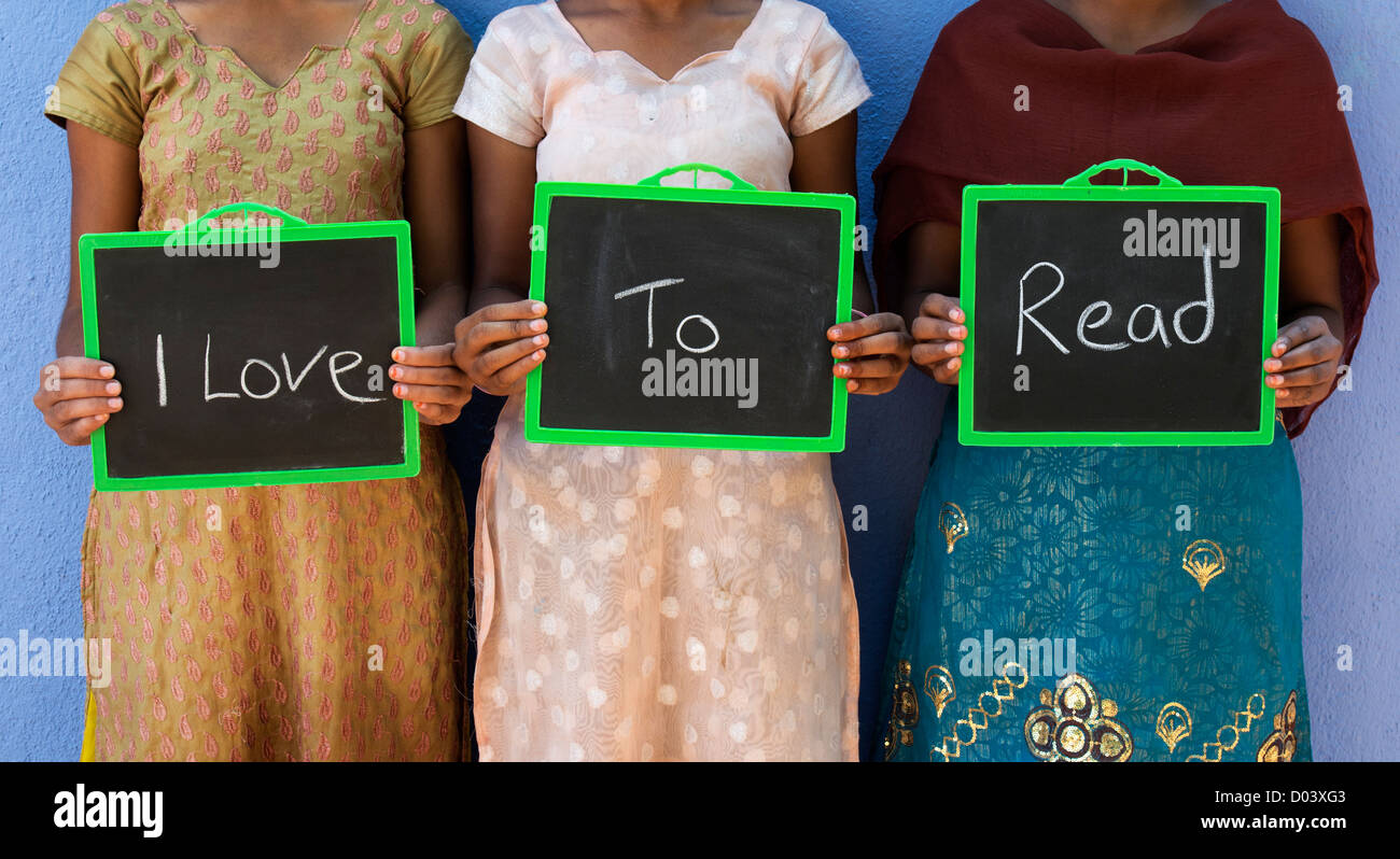 Drei Indianerdorf Schulmädchen mit ich Liebe zu lesen, auf einer Tafel geschrieben. Andhra Pradesh, Indien Stockfoto