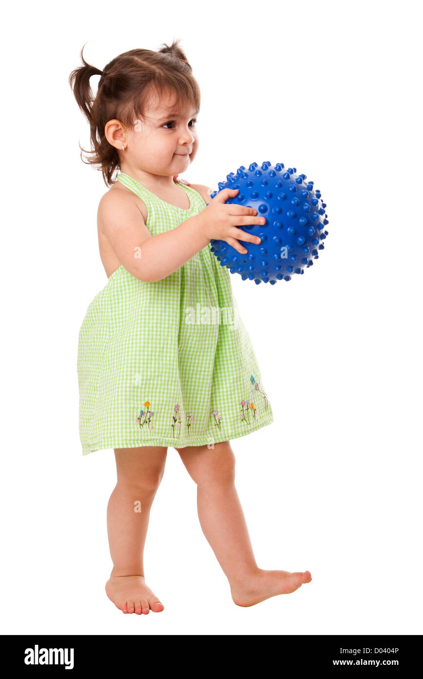 Schöne süße glücklich Kleinkind Baby Mädchen in grünen Kleid zu Fuß, mit blauen stacheligen Ball, isoliert zu spielen. Stockfoto