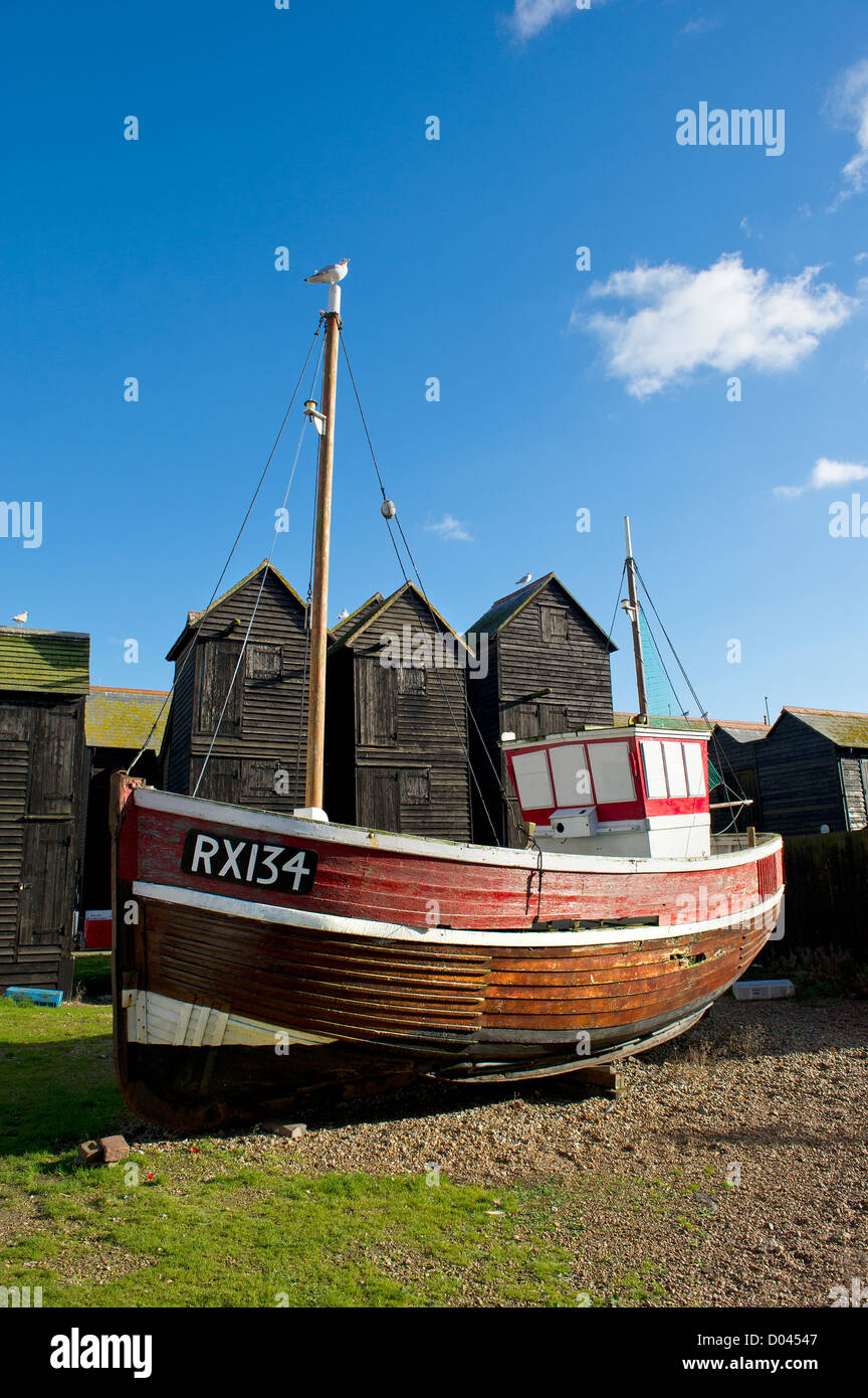 Ein traditionelles historisches Holzfischerboot, das in Old Hastings in Kent ausgestellt wird, mit alten, netztrocknenden Gebäuden im Hintergrund. Stockfoto