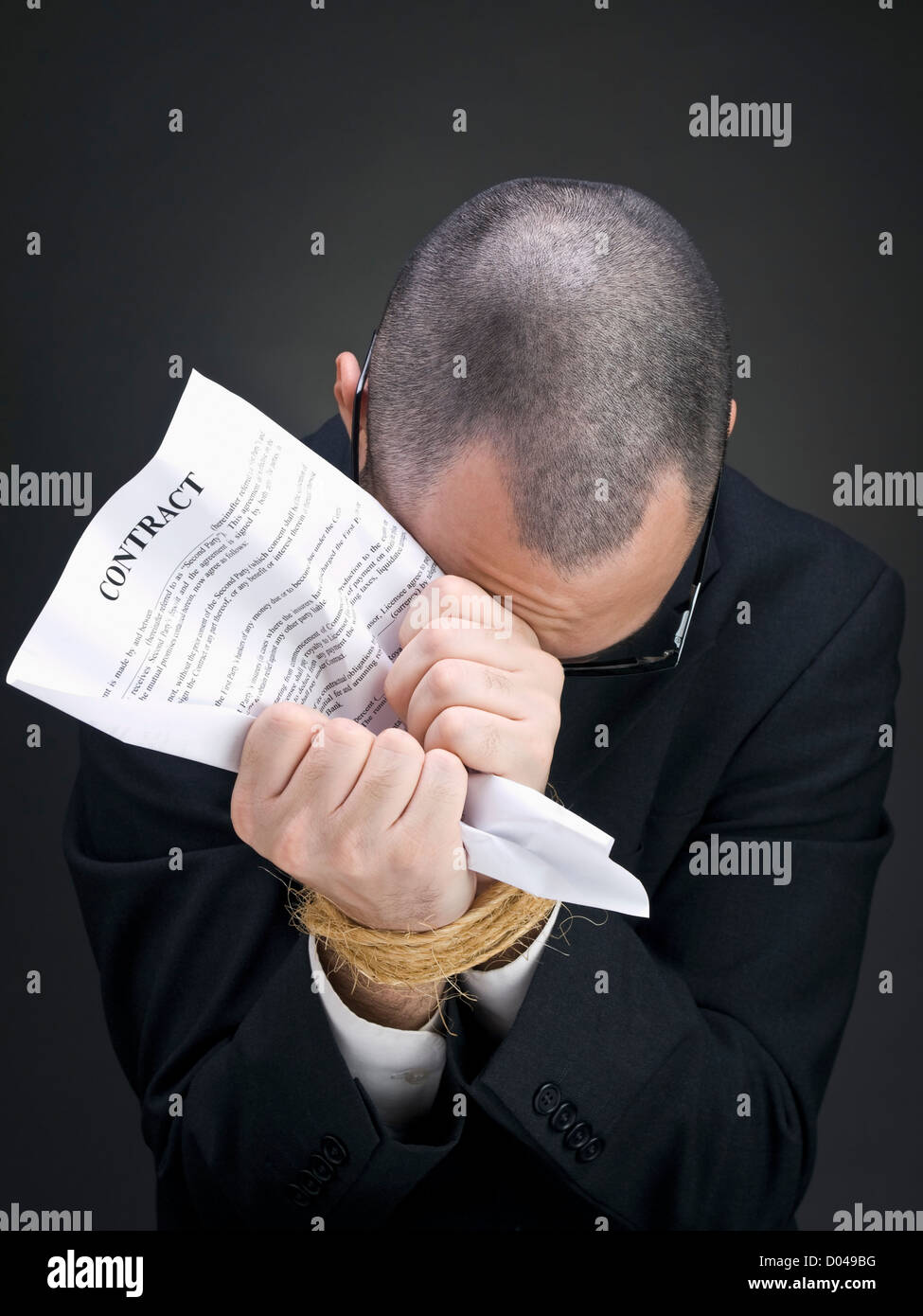 Ein Mann auf einem Anzug hält einen Vertrag auf seinen gefesselten Händen. Stockfoto