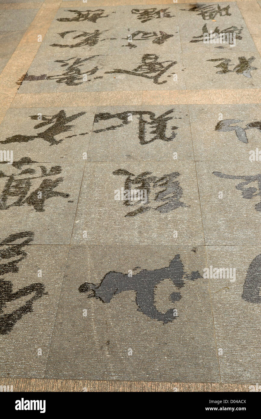 Chinesische Schriftzeichen mit Wasser auf Bürgersteig gezeichnet Stockfoto