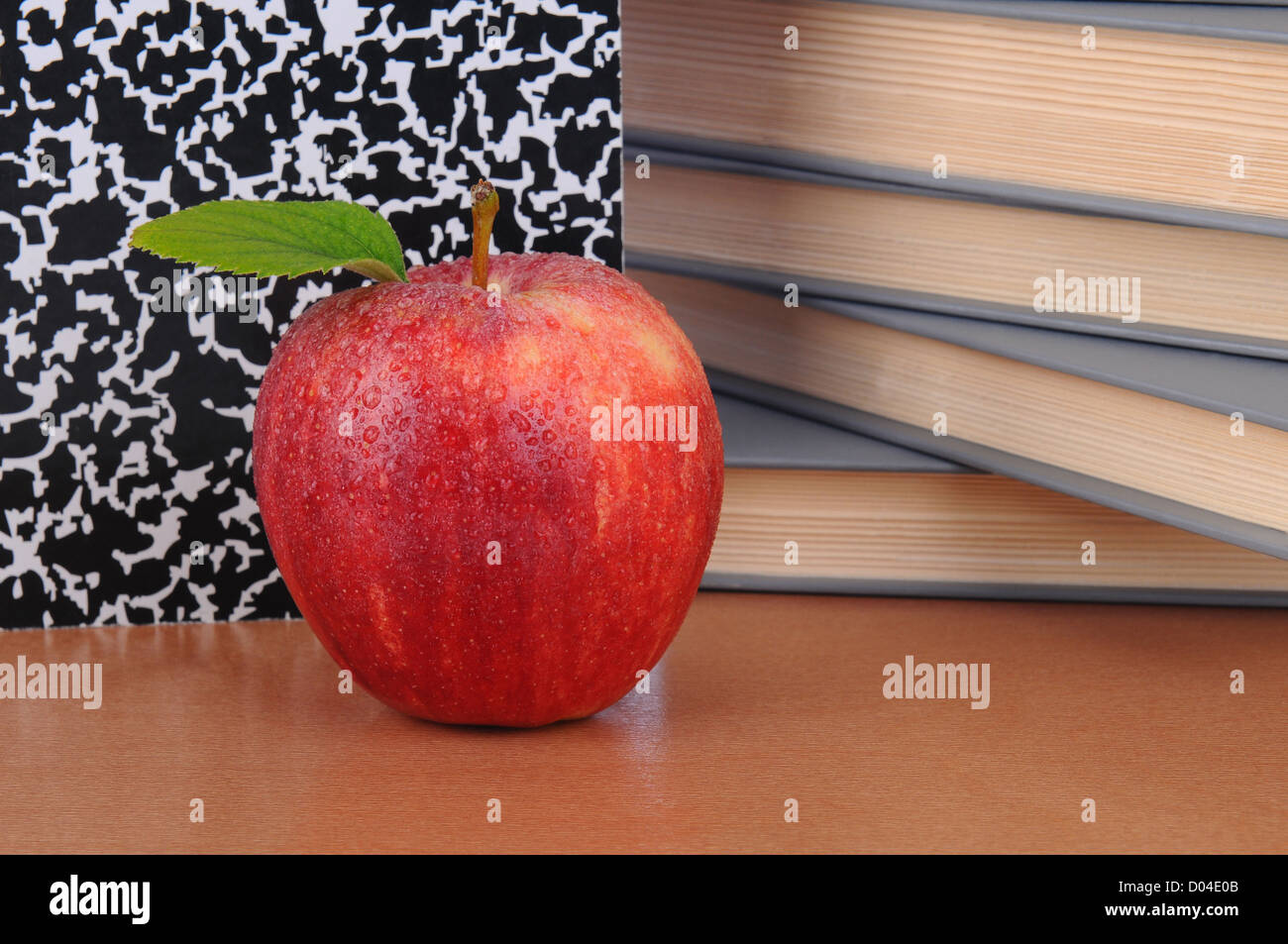 Nahaufnahme eines roten Apfels auf einem Lehrer Schreibtisch. Bücher und Zusammensetzung Buch bilden den Hintergrund. Querformat. Stockfoto