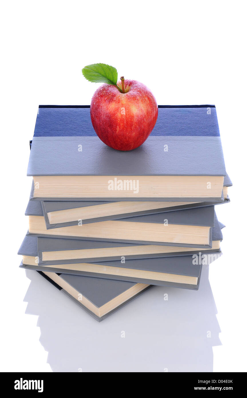 Ein roter Gala Apfel auf einem Stapel Bücher. Hochformat auf weiß mit Reflexion. Stockfoto