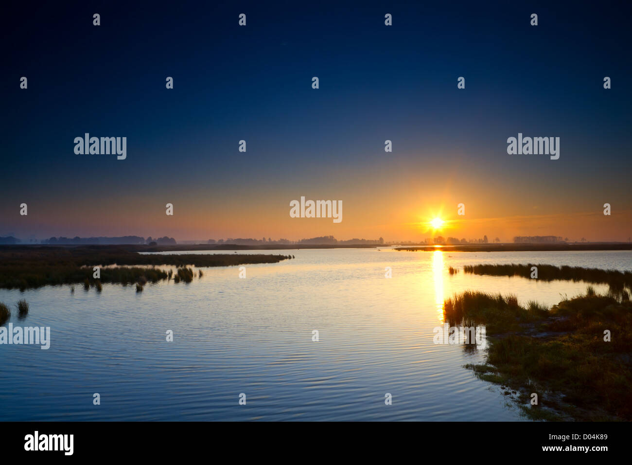 Sonne am Sonnenaufgang über dem blauen See in Drenthe, Niederlande Stockfoto