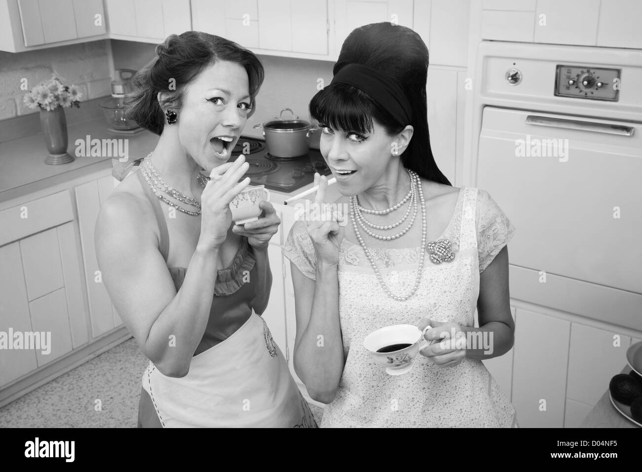 Zwei Frauen rauchen Zigaretten beim Kaffeetrinken in einer Retro-Küche-Szene Stockfoto