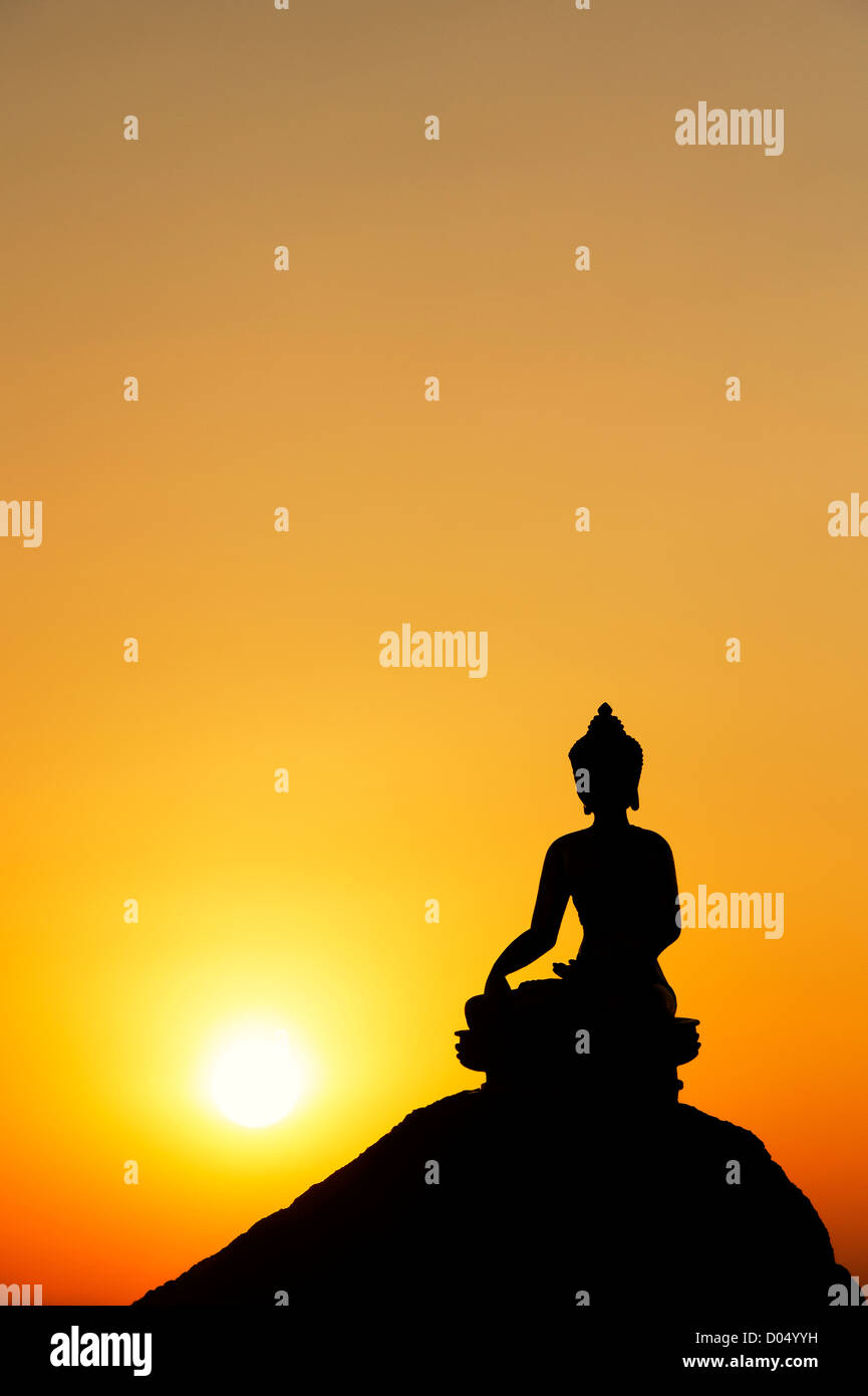 Buddha-Statue vor einer untergehenden Sonne. Silhouette Stockfoto