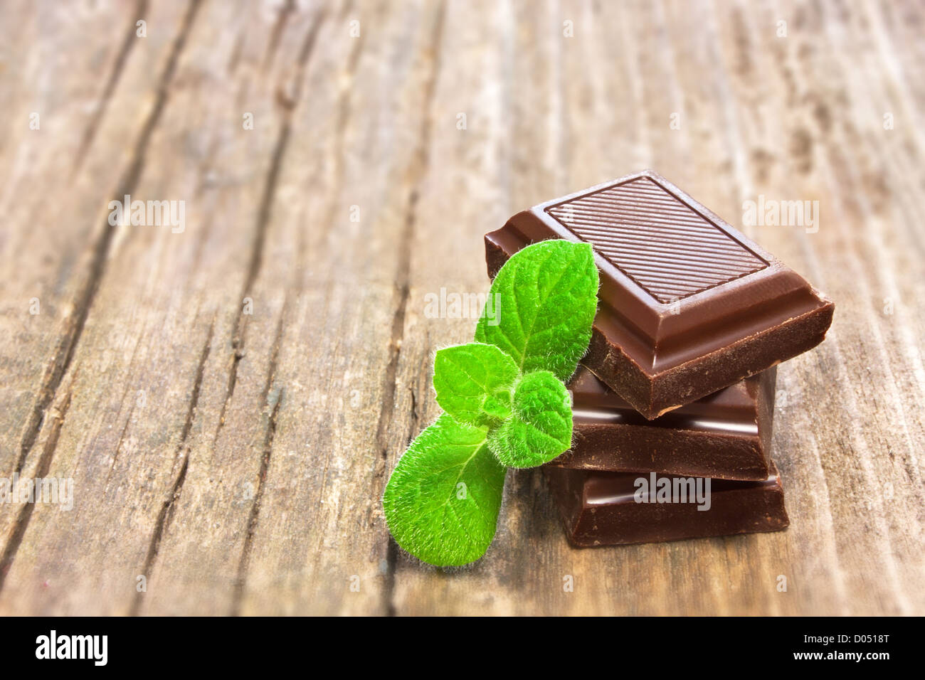 Dunkler Schokolade mit frischer Minze Blätter auf hölzernen Hintergrund Stockfoto