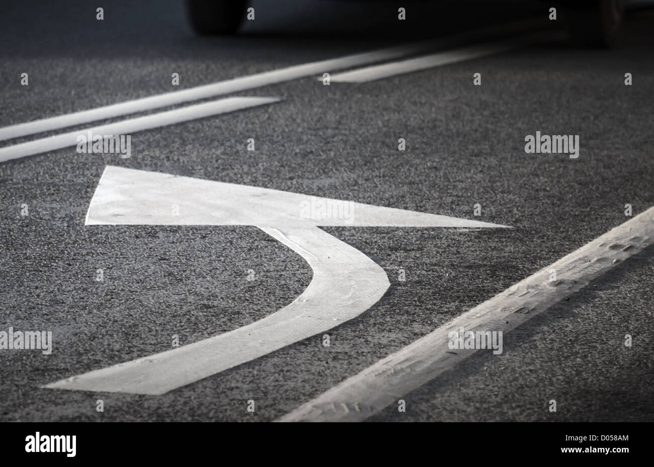 Straßenmarkierung. Weißen Pfeil und Linien auf dunklem Asphalt drehen. Stockfoto