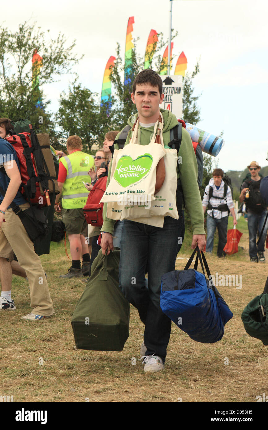 Glastonbury Festival - kommt jungen männlichen Fans vor Ort mit vielen Taschen Gepäck für das Festivalwochenende Stockfoto
