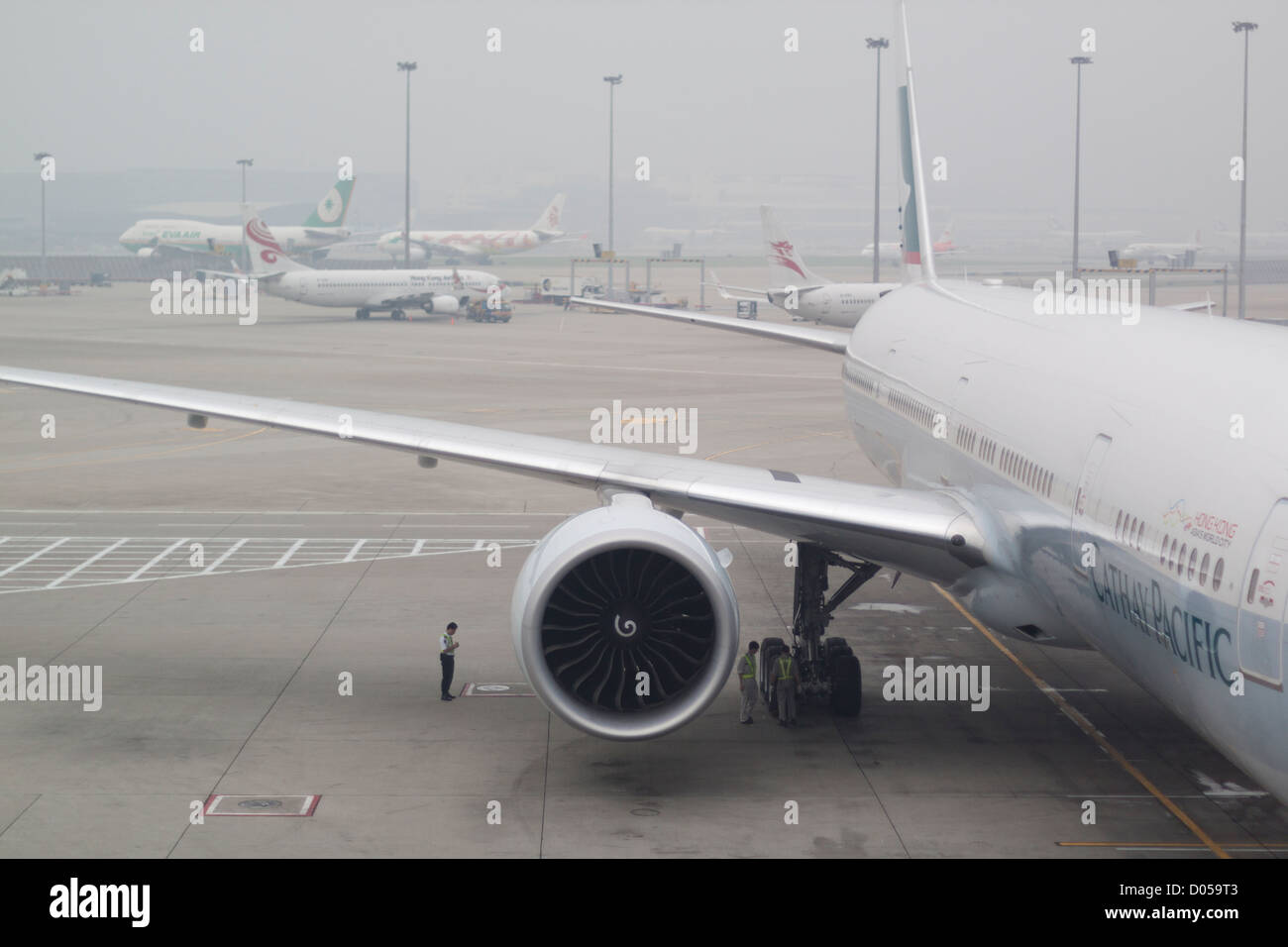 Neben einem Cathay Pacific Flugzeug Jet-Engine mit anderen Flugzeugen im Hintergrund stehende Person Stockfoto