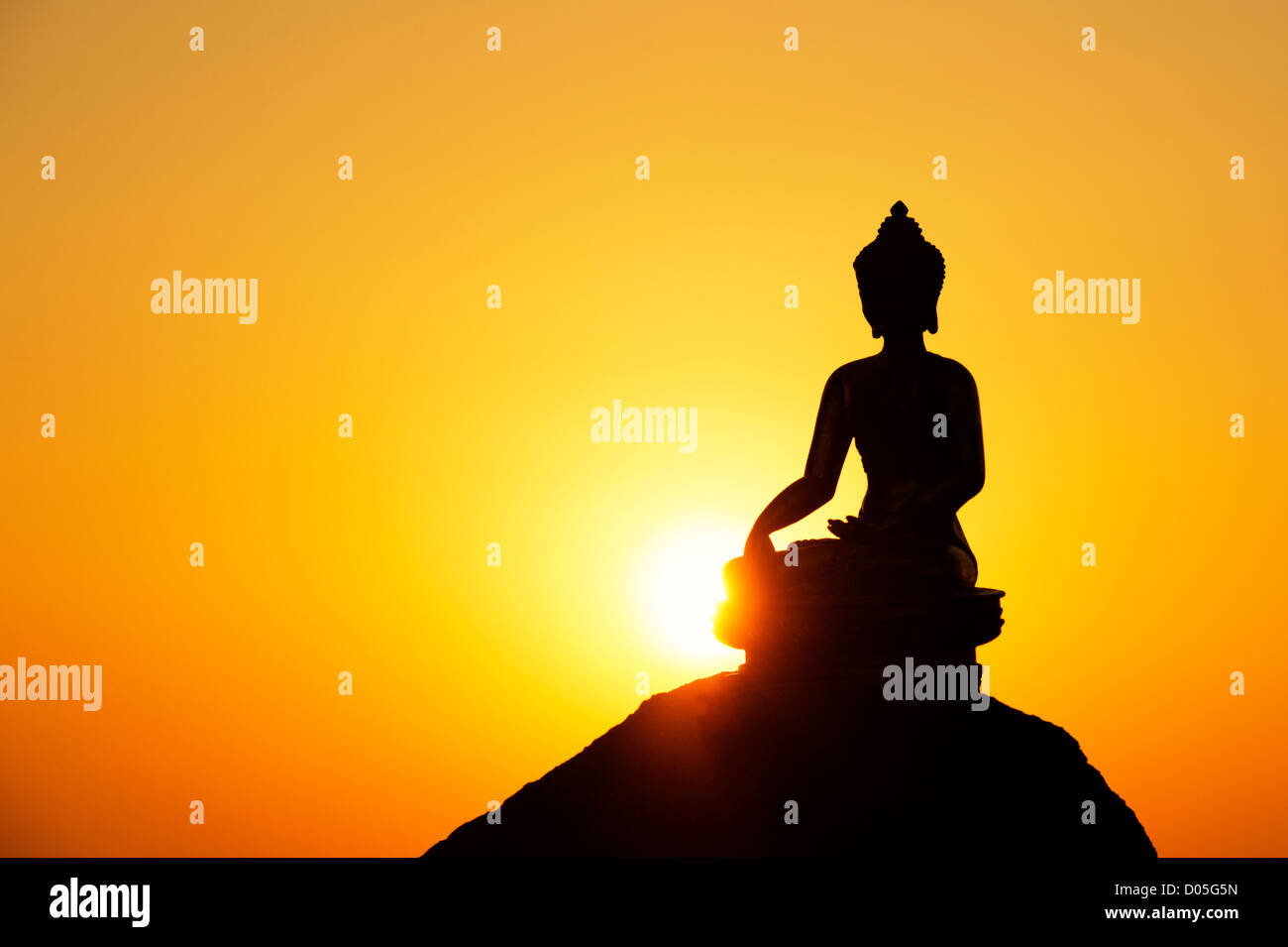 Buddha-Statue vor einer untergehenden Sonne. Silhouette Stockfoto