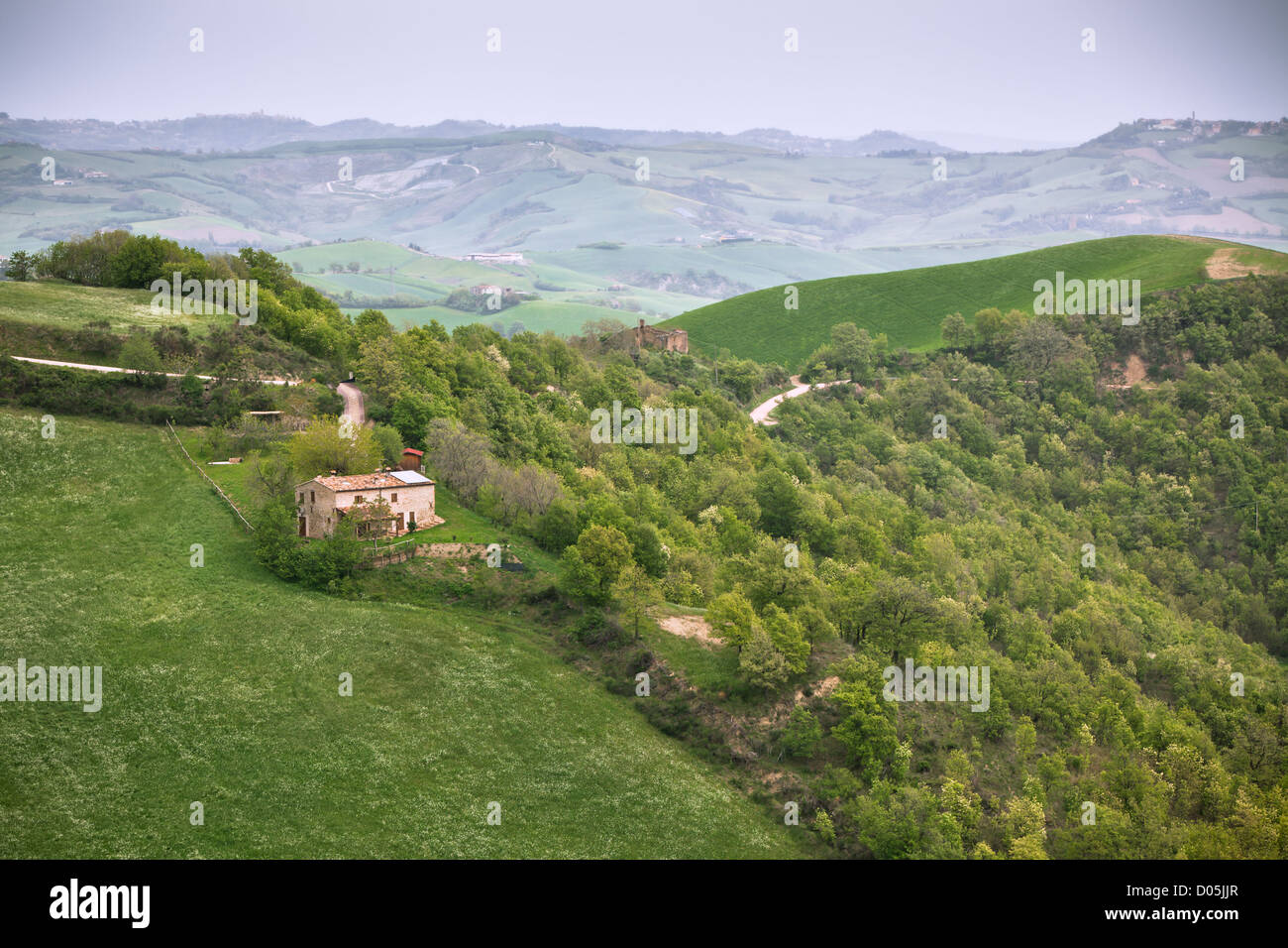 Schlechtes Wetter in Italien Ackerland. Grüne Hügel und Bauernhaus Stockfoto