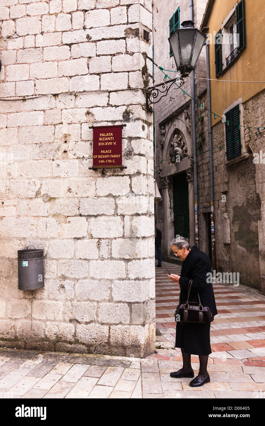 Alte Dame gekleidet im schwarzen Blick auf ihr Handy. Alten Schlepptau, Kotor, Montenegro Stockfoto