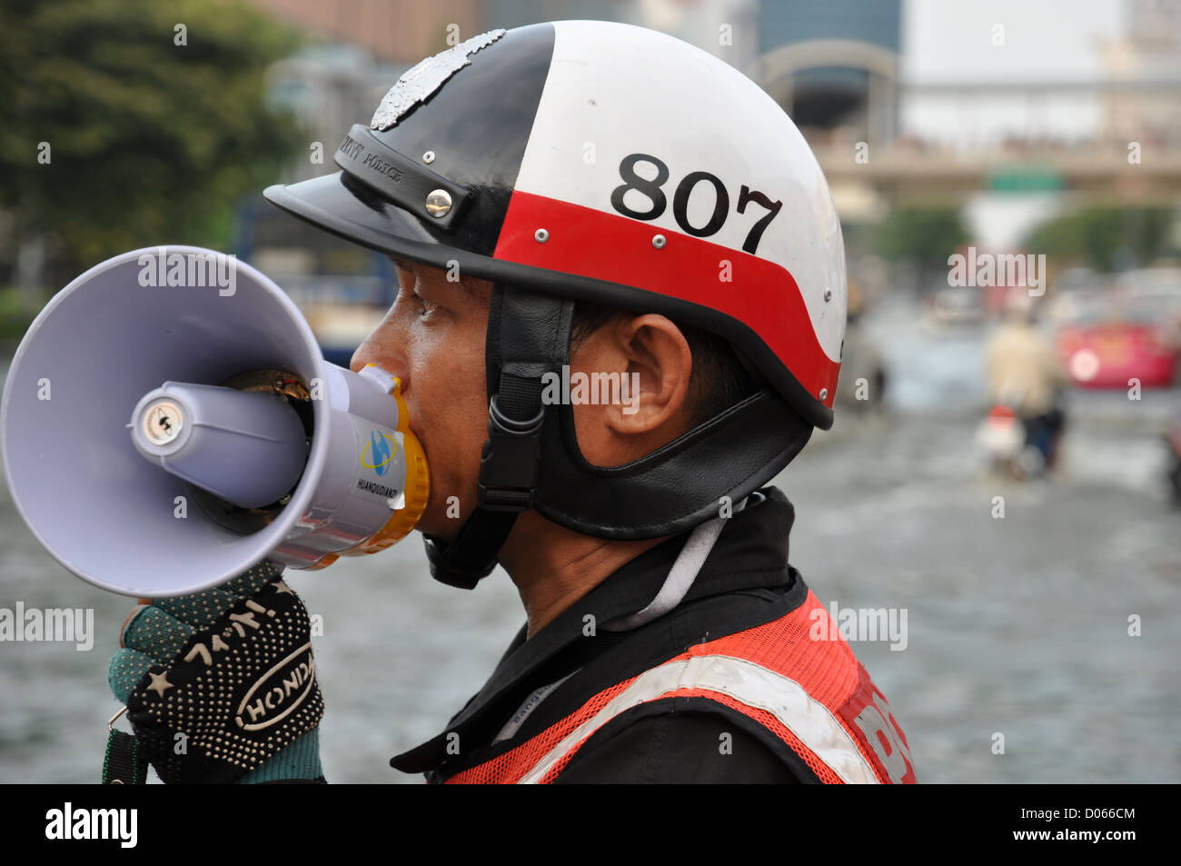 Thailändischen Verkehrspolizei regelt den Verkehr auf der überfluteten Straße Bangkoks. Stockfoto