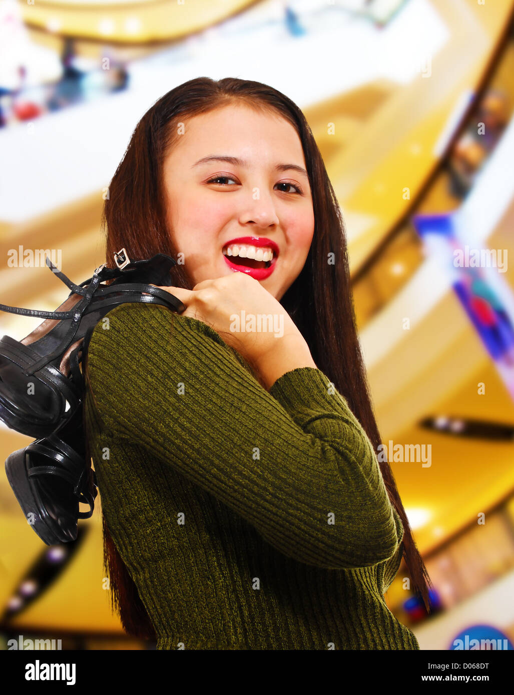 Lächelnde Teenager in einem Einkaufszentrum halten ihre Schuhe über die Schulter Stockfoto
