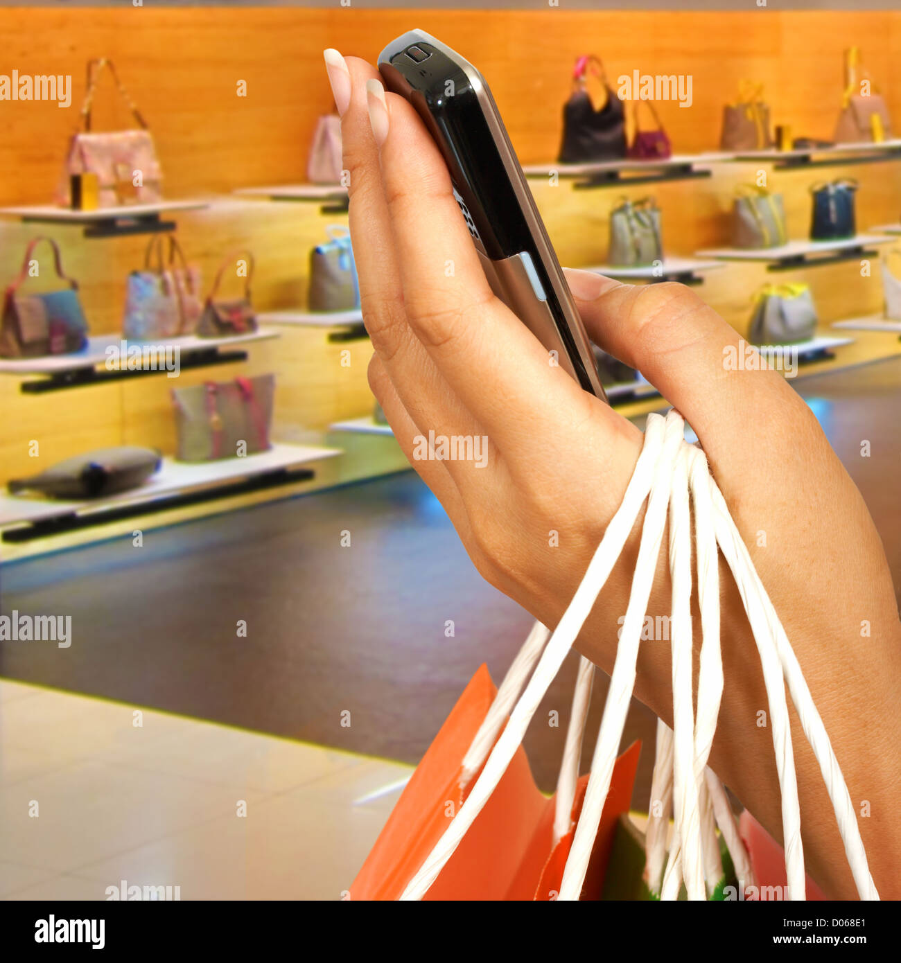 Tätigen eines Anrufs In einem Einkaufszentrum außerhalb ein Handtaschengeschäft Stockfoto