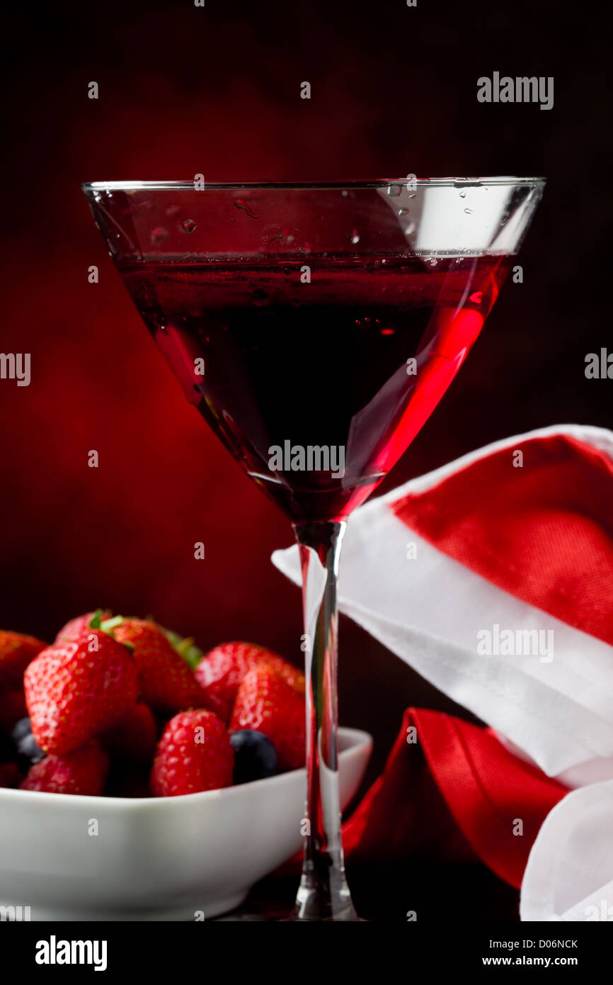 Foto von Kelch mit Cocktail mit Beeren auf rot beleuchteten backgroud Stockfoto