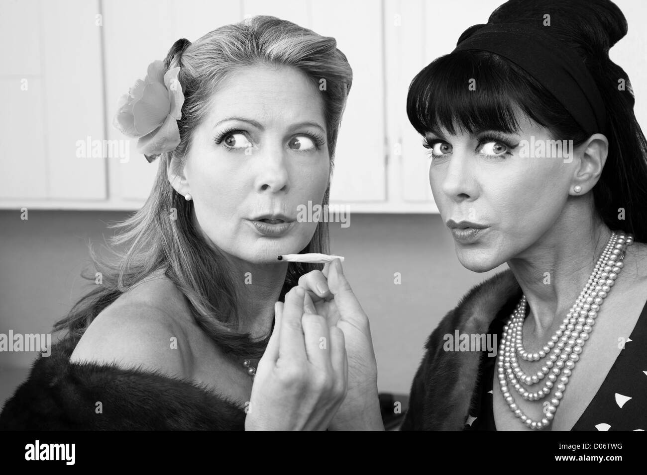 Hinterhältige reichen Hausfrauen teilen ein Marihuana-Gelenk in Küche Stockfoto